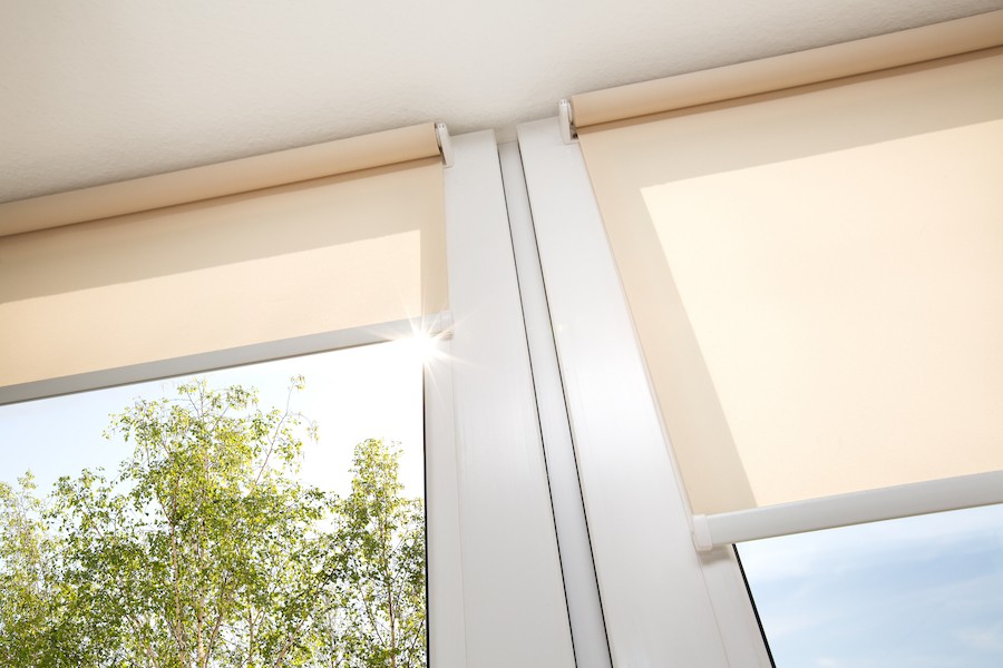 Side-by-side windows featuring half-opened cream-colored motorized shades.