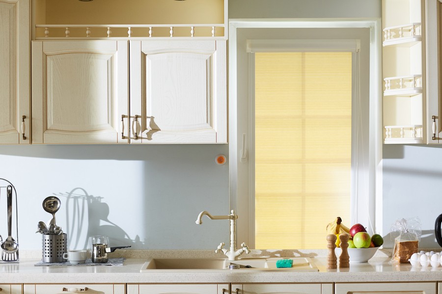 Interior shot of a kitchen counter with a sink and fruit bowl–all lit by sunlight.